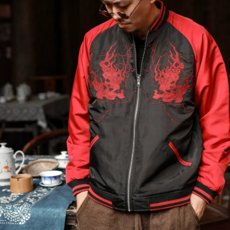 Person wearing a black and red jacket with dragon designs in a dimly lit room.