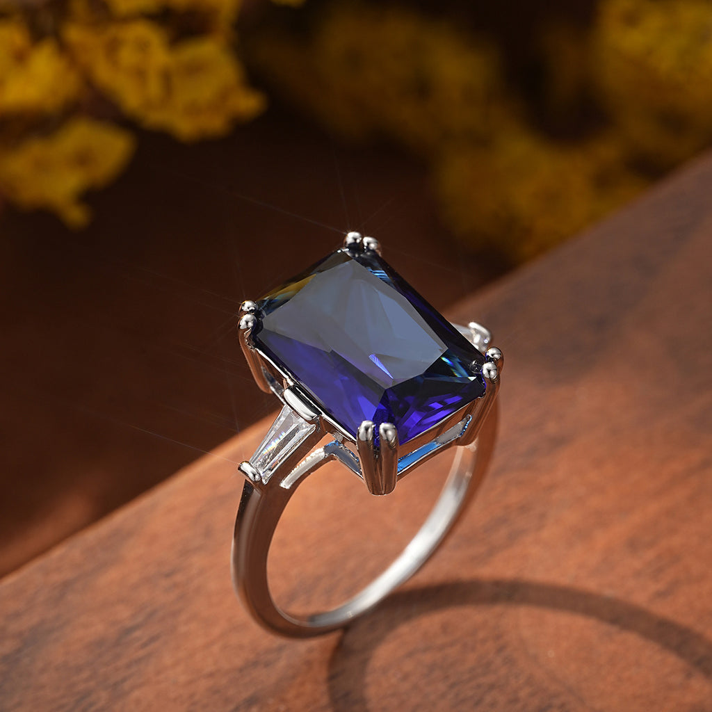 Silver ring with a large purple gemstone on a wooden surface