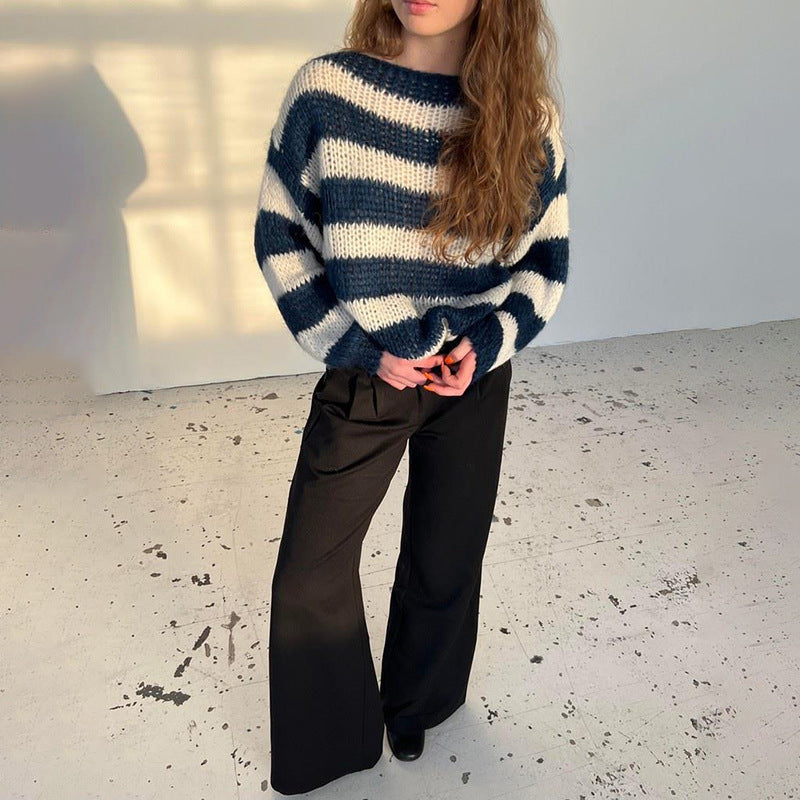 Person wearing a blue and white striped sweater and black pants in a minimal indoor setting, 
Mordenstore. 